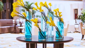 Un vestíbulo con una mesa redonda que sostiene jarrones con flores amarillas.