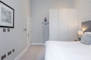 A hotel room with a bed, a wardrobe, a towel rack, and a framed picture on the wall. - Chilworth Court (London)