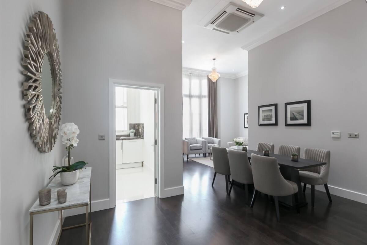 A modern dining area with a dark wood table and chairs, a decorative mirror, and framed pictures on the wall.