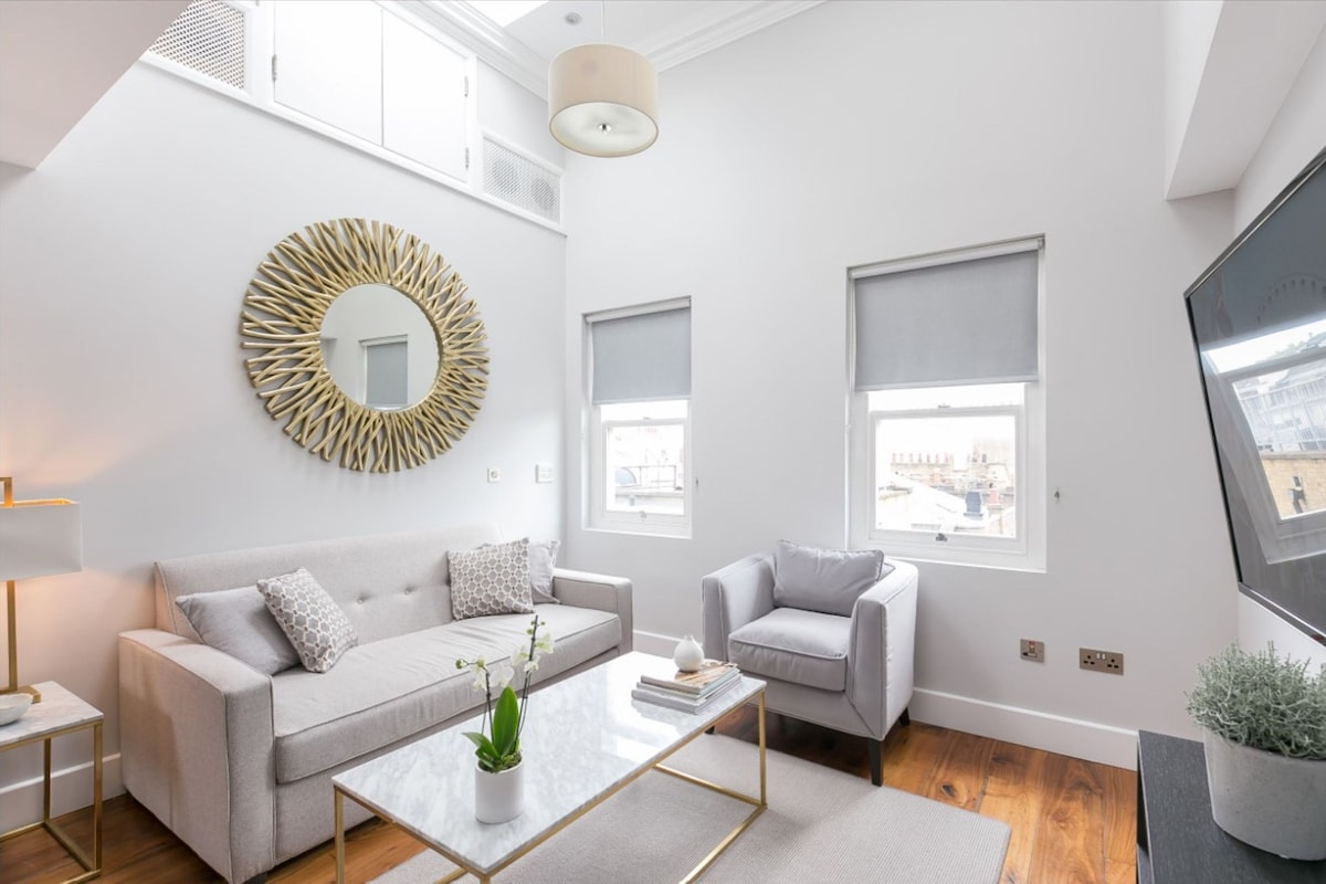 A modern living room with a sofa, armchair, coffee table, and a large mirror.