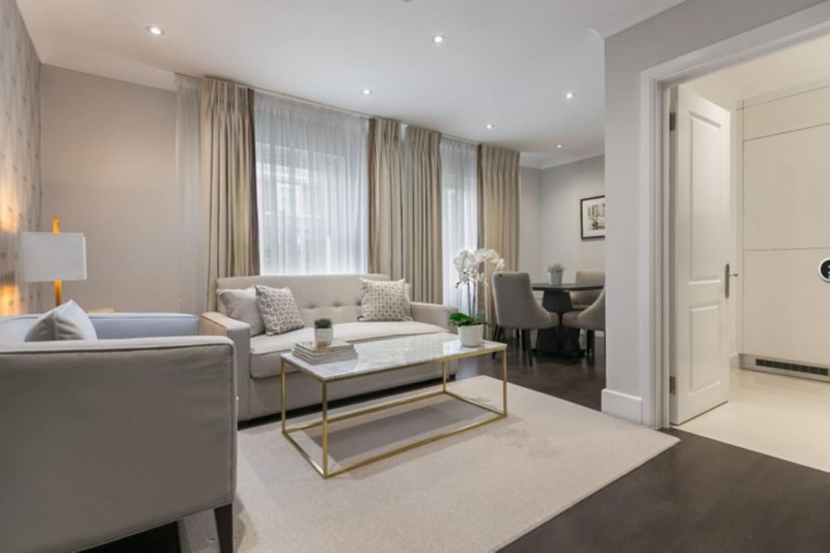 A modern living room with a sofa, coffee table, and a dining area with a table and chairs.