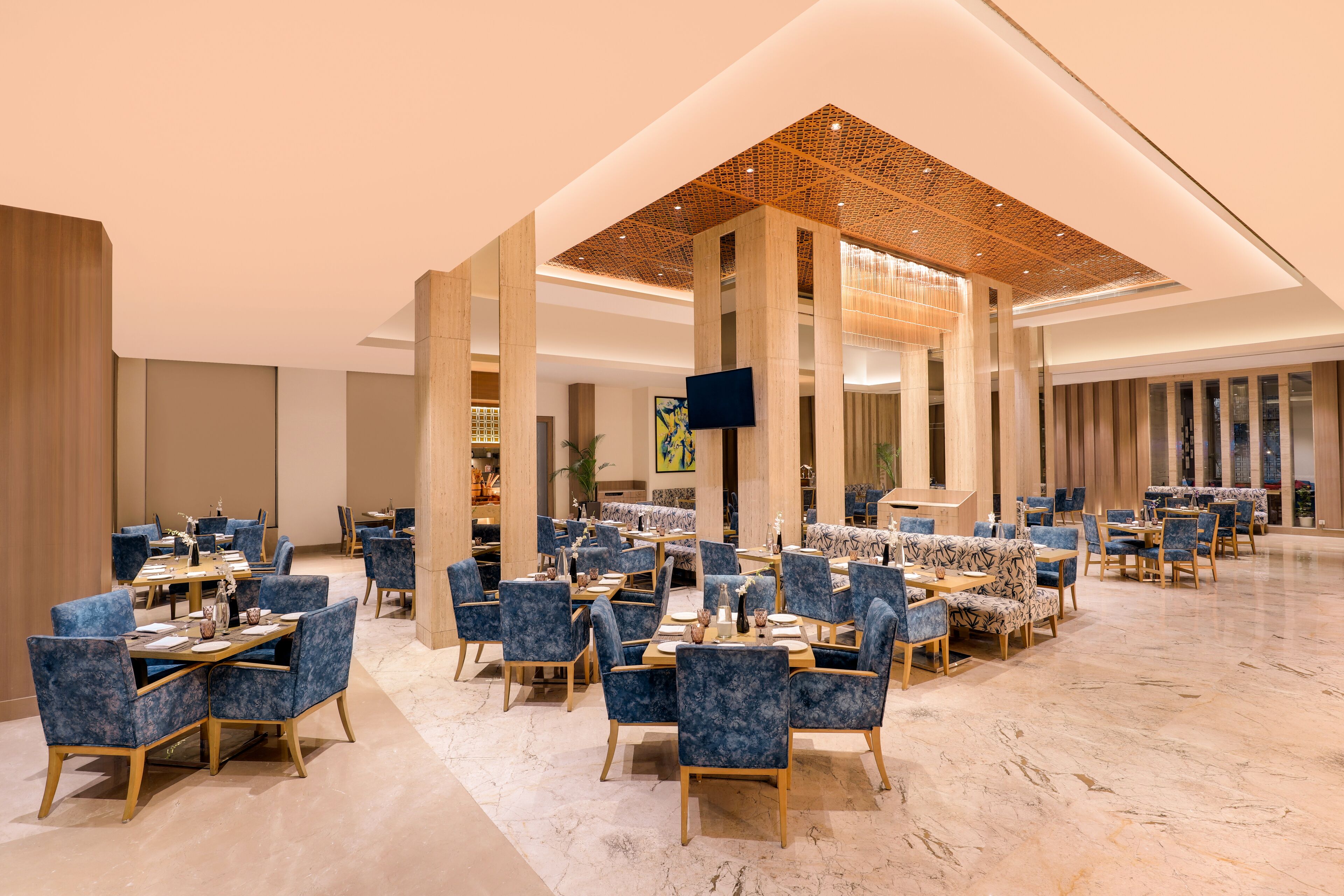 Un'ampia hall dell'hotel con diverse zone salotto, un grande schermo televisivo e un moderno design del soffitto.