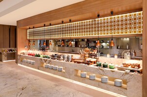 Montaje de bufé con encimera de mármol, diferentes opciones de comida y un panel de luces decorativo.