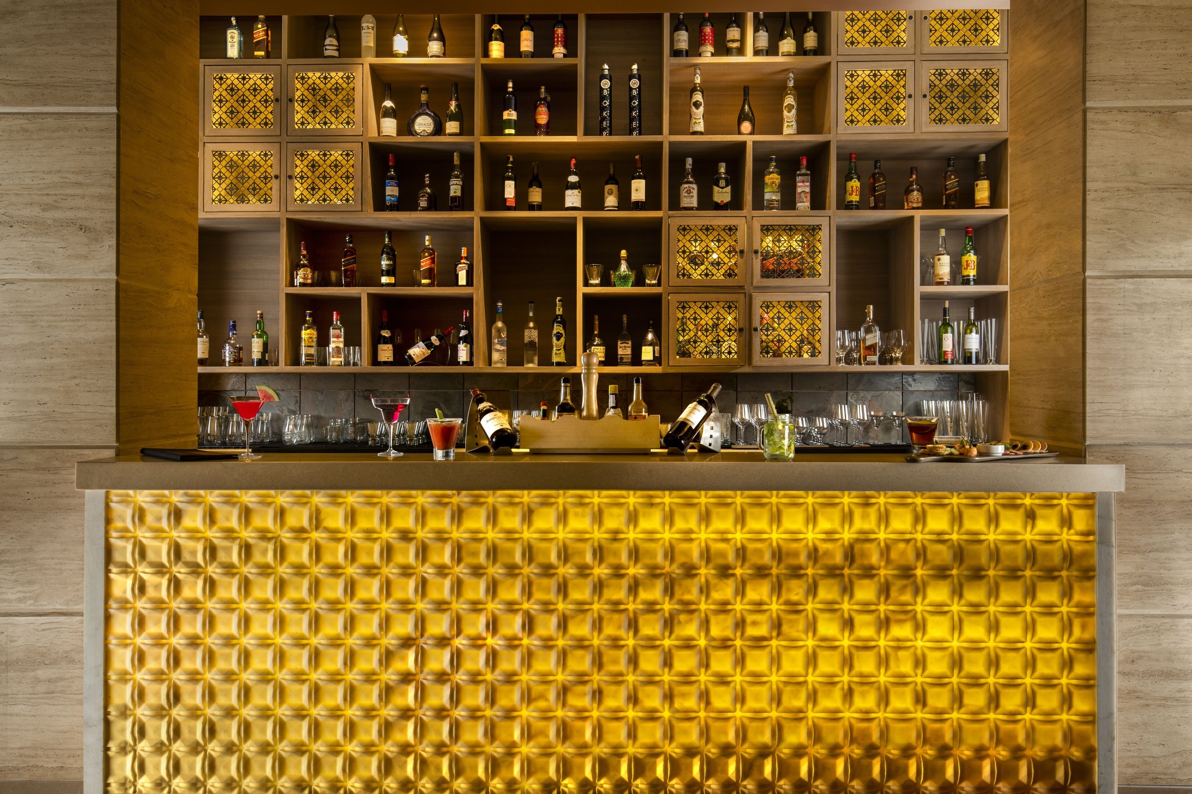 Zona de bar con estantes llenos de botellas de licor y vasos.