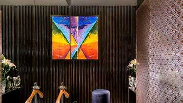 A modern reception area with a marble floor, a colorful abstract painting, and a patterned wall.