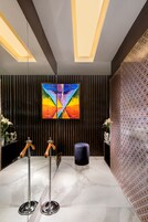A modern reception area with a marble floor, a colorful abstract painting, and a patterned wall.