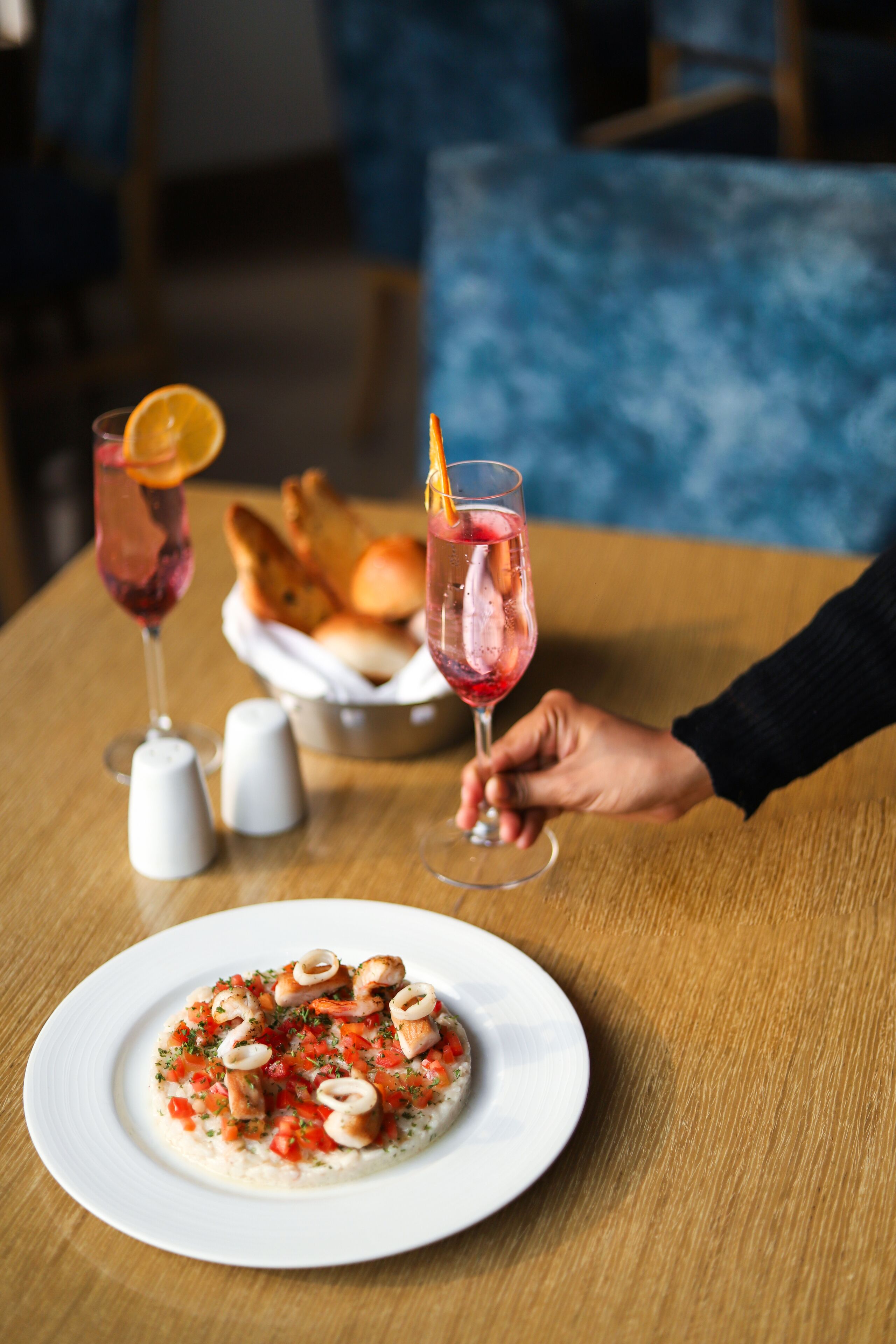 A dining table with a plate of food and two glasses of drink.
