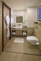 Ein modernes Badezimmer mit Holztür, weißem Waschbecken, Spiegel, Toilette und Handtuchhalter.