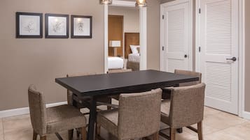 Un comedor con una mesa rectangular, seis sillas, dos lámparas colgantes y tres obras de arte enmarcadas en la pared.