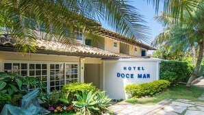 A hotel entrance with a sign reading "Hotel Doce Mar" surrounded by lush greenery and palm trees. - Hotel Doce Mar (Búzios)