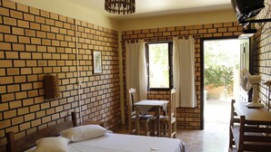 A room with a brick wall, a bed, a table, and a chair. - Alecrim Pousada (Garopaba)