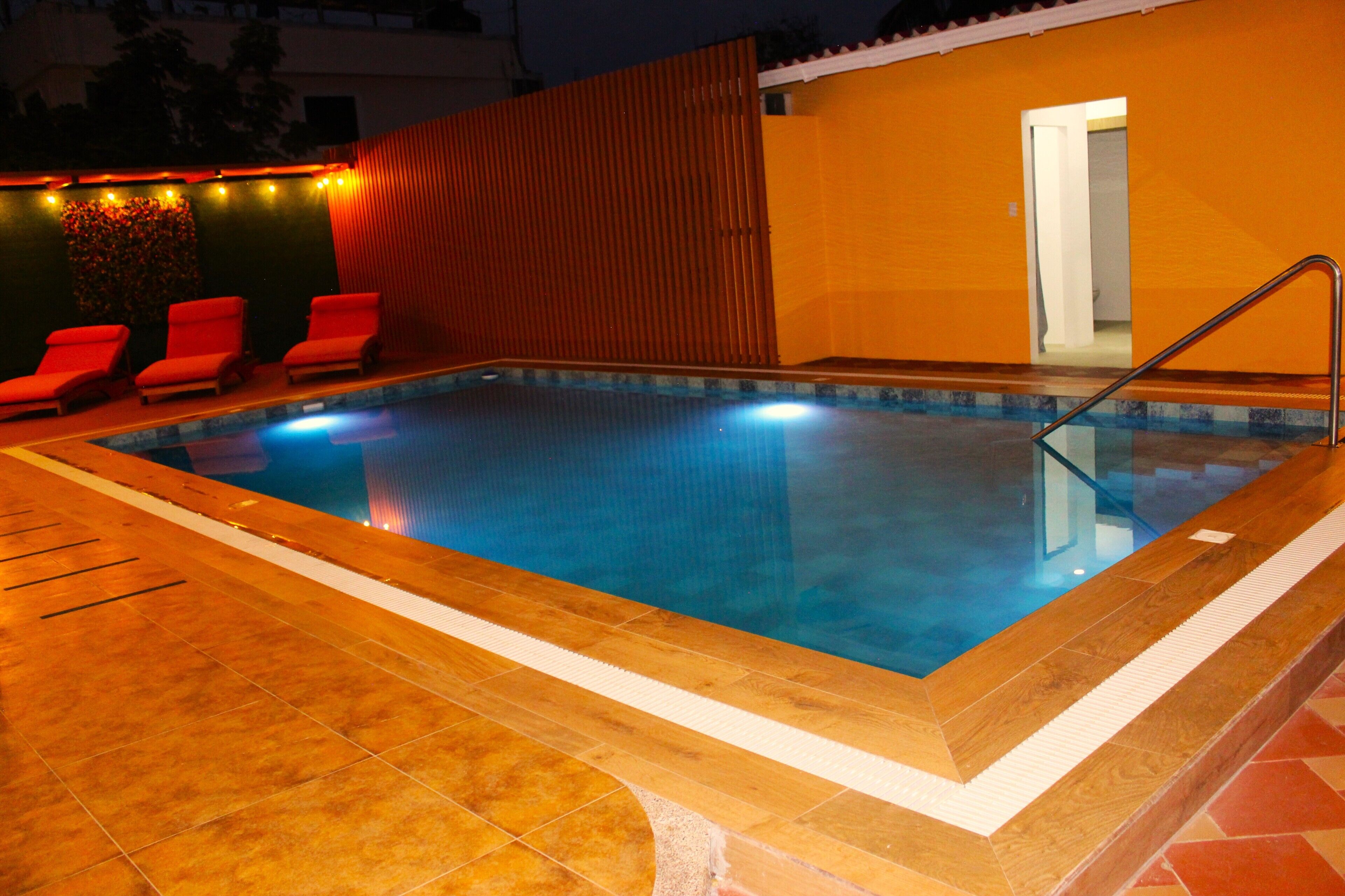A swimming pool with a tiled edge, a wooden deck, and a red chair.