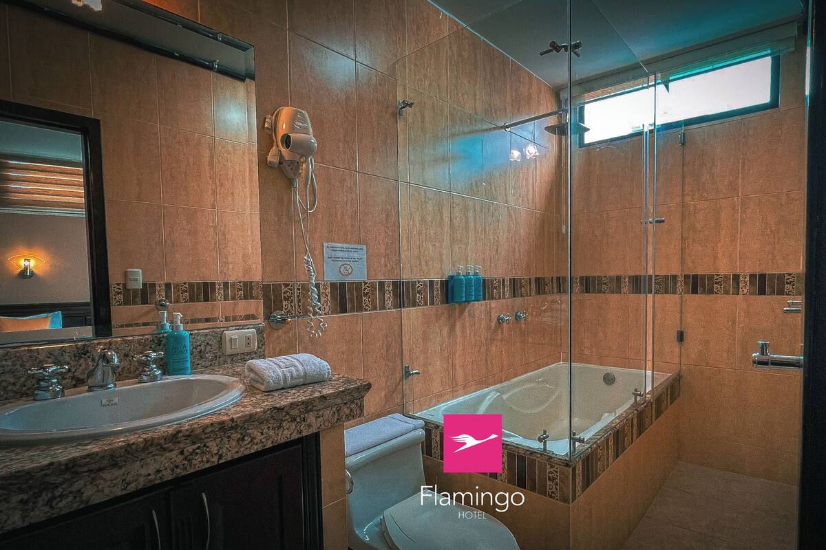 A modern bathroom with a large mirror, two sinks, a shower, and a bathtub.