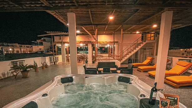 A hot tub area with lounge chairs, a staircase, and a poolside seating area. - Hotel Flamingo (Puerto Ayora)