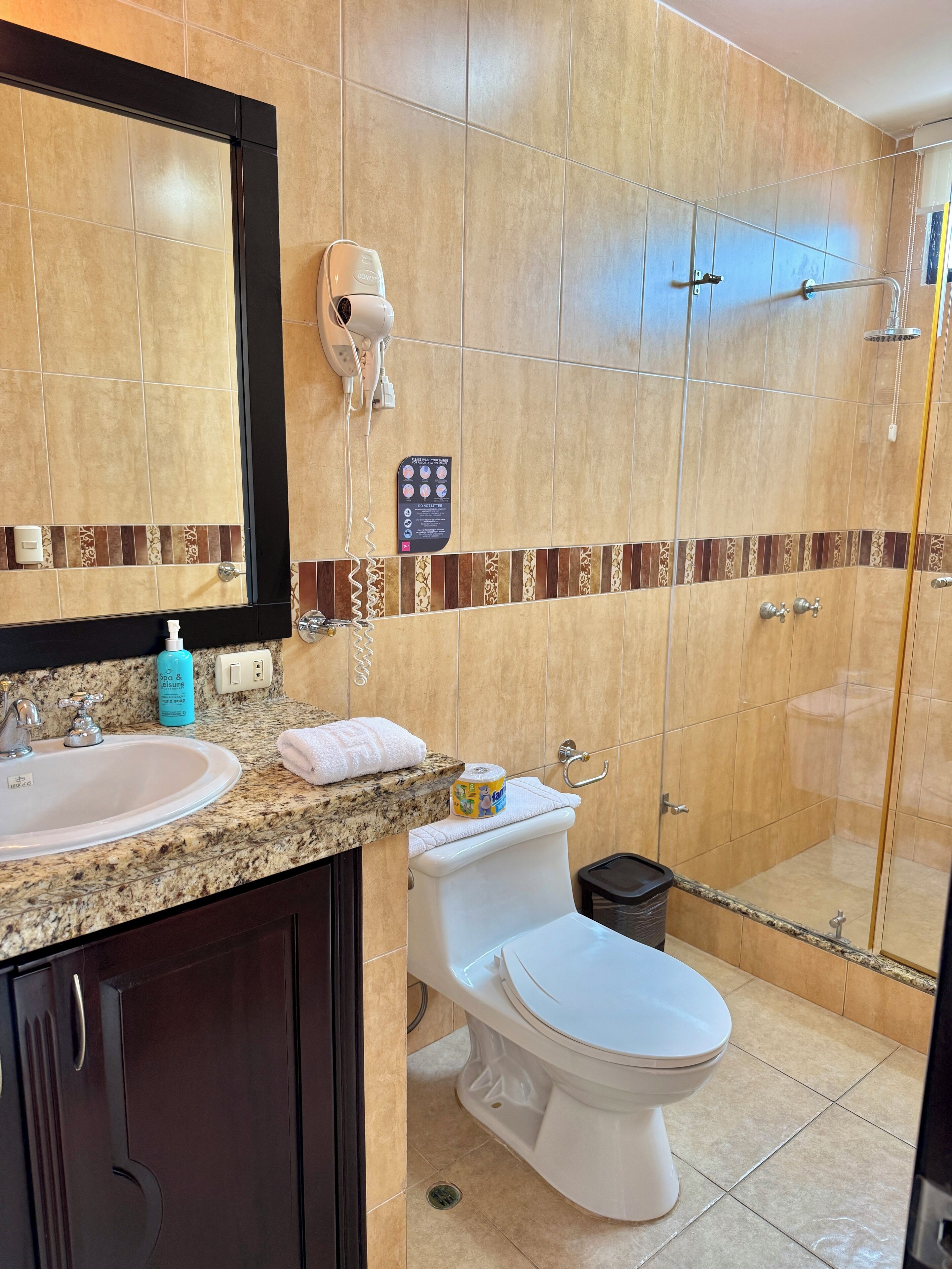 Une salle de bain équipée d’un lavabo, d’un miroir, d’une serviette, de toilettes et d’une douche.