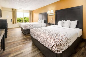 A hotel room with two beds, a desk, and a window with curtains.