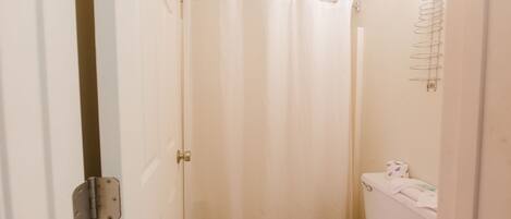 A small, clean bathroom with a toilet, a shower curtain, and a toilet paper holder.