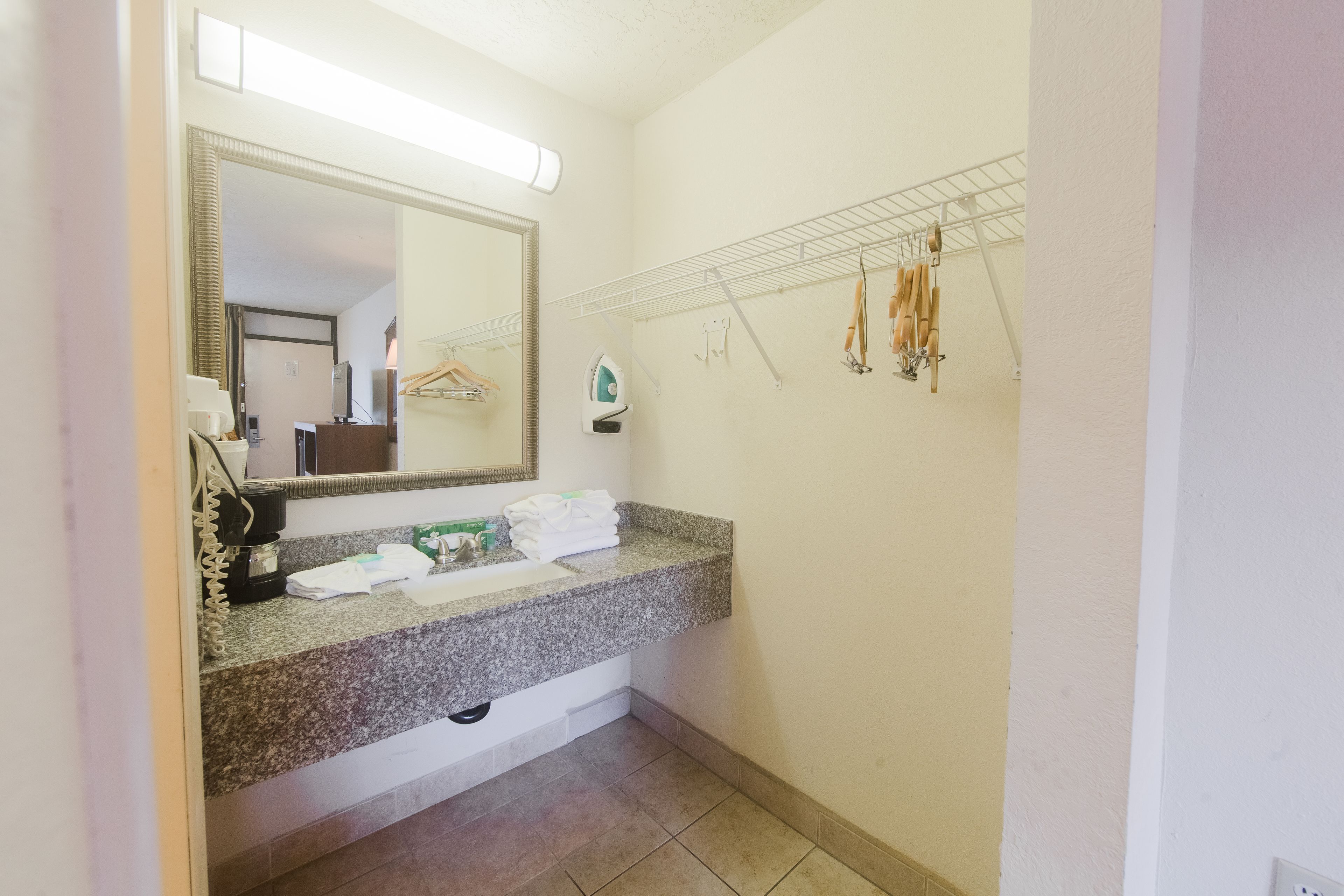 A bathroom with a granite countertop, a large mirror, a towel rack, and a wall-mounted heater.
