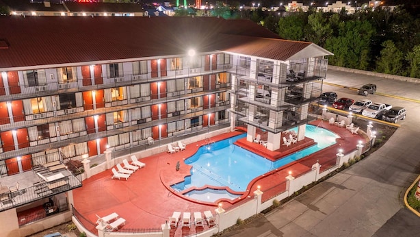 A multi-story hotel with a swimming pool and outdoor seating. - Americana Inn, a Travelodge by Wyndham (Pigeon Forge)