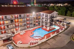 A multi-story hotel with a swimming pool and outdoor seating.