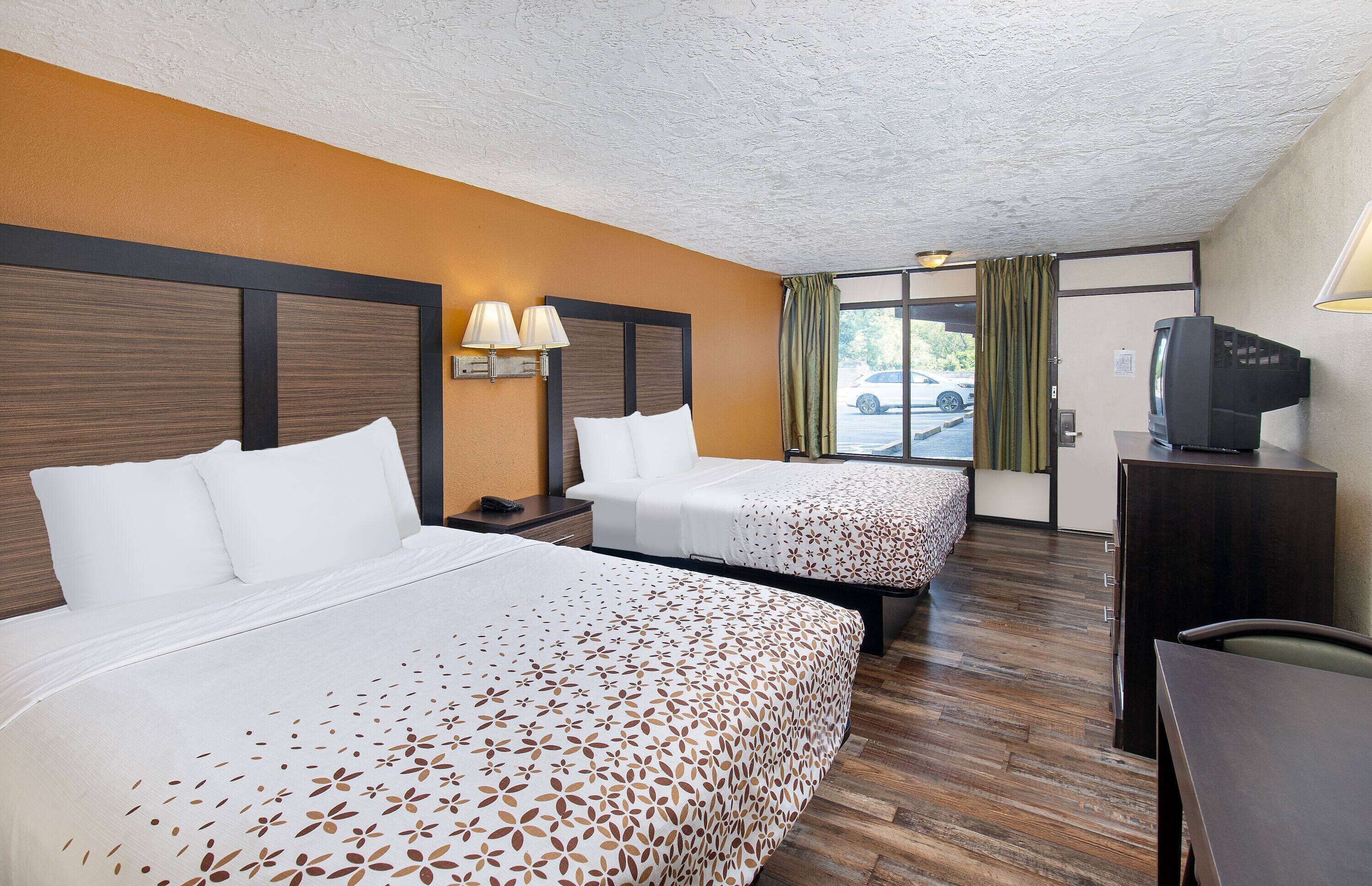 Una habitación de hotel con dos camas, televisión y escritorio.