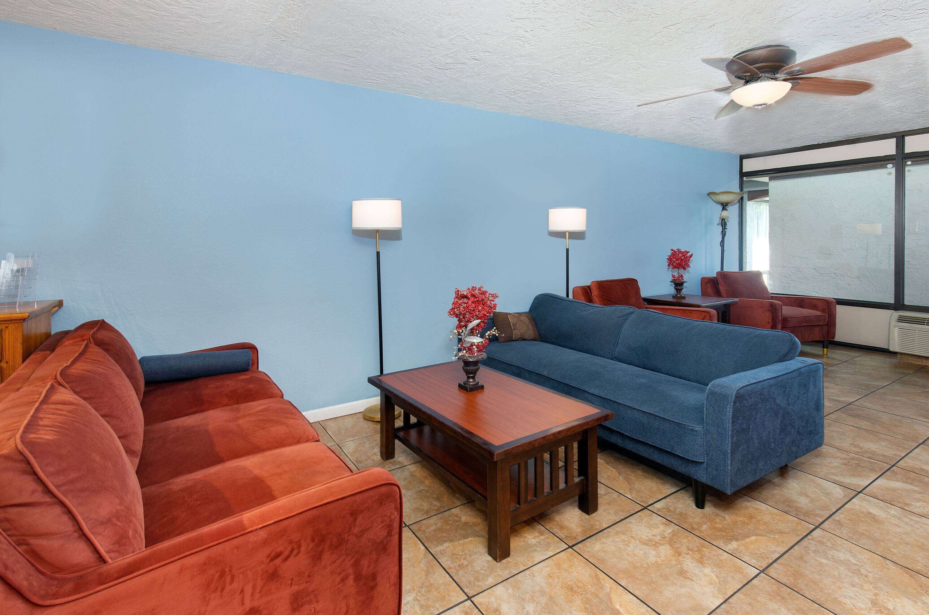A living room with a blue sofa, a red sofa, a wooden coffee table, and two floor lamps.