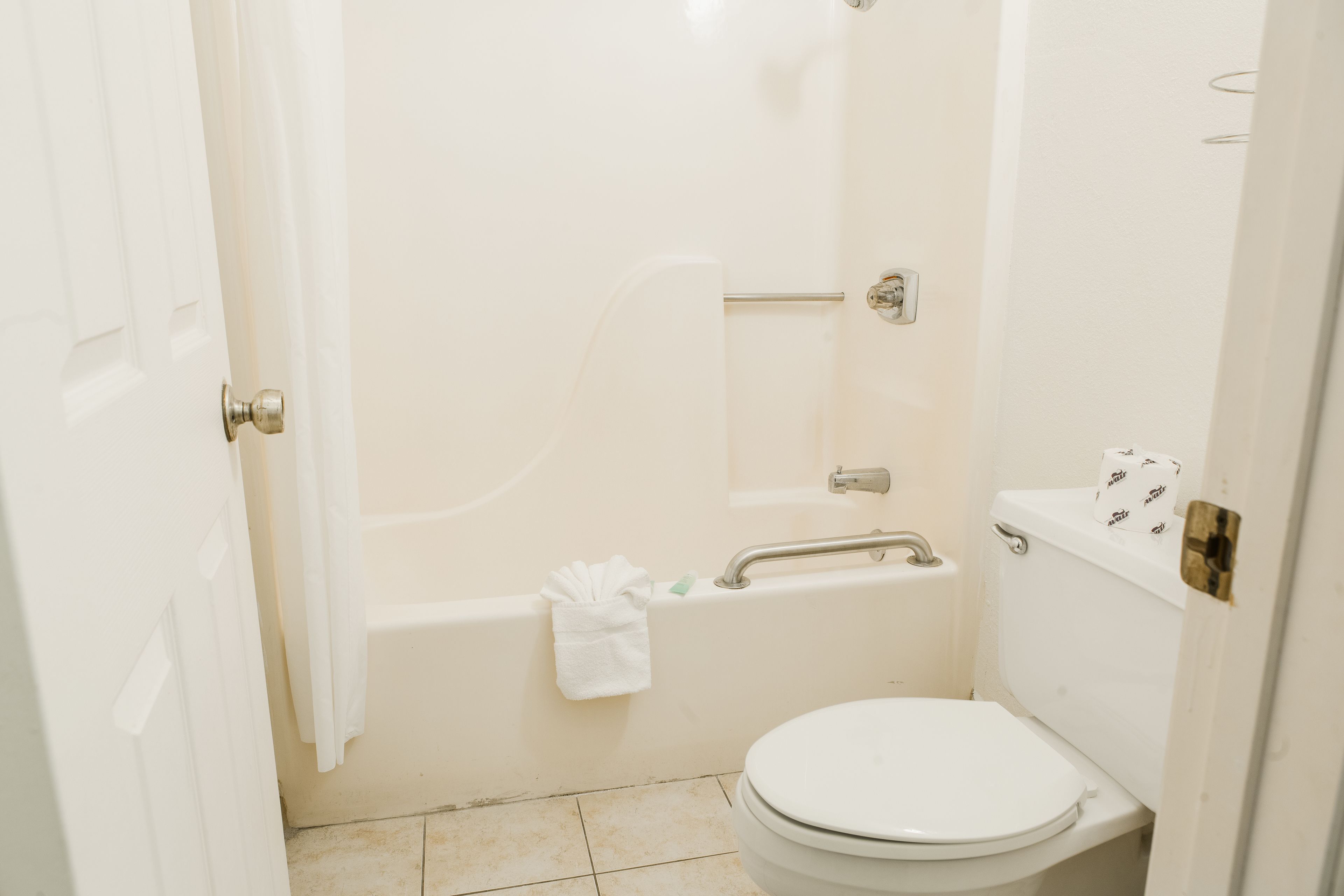 A small, white bathroom with a toilet, a bathtub, and a shower.