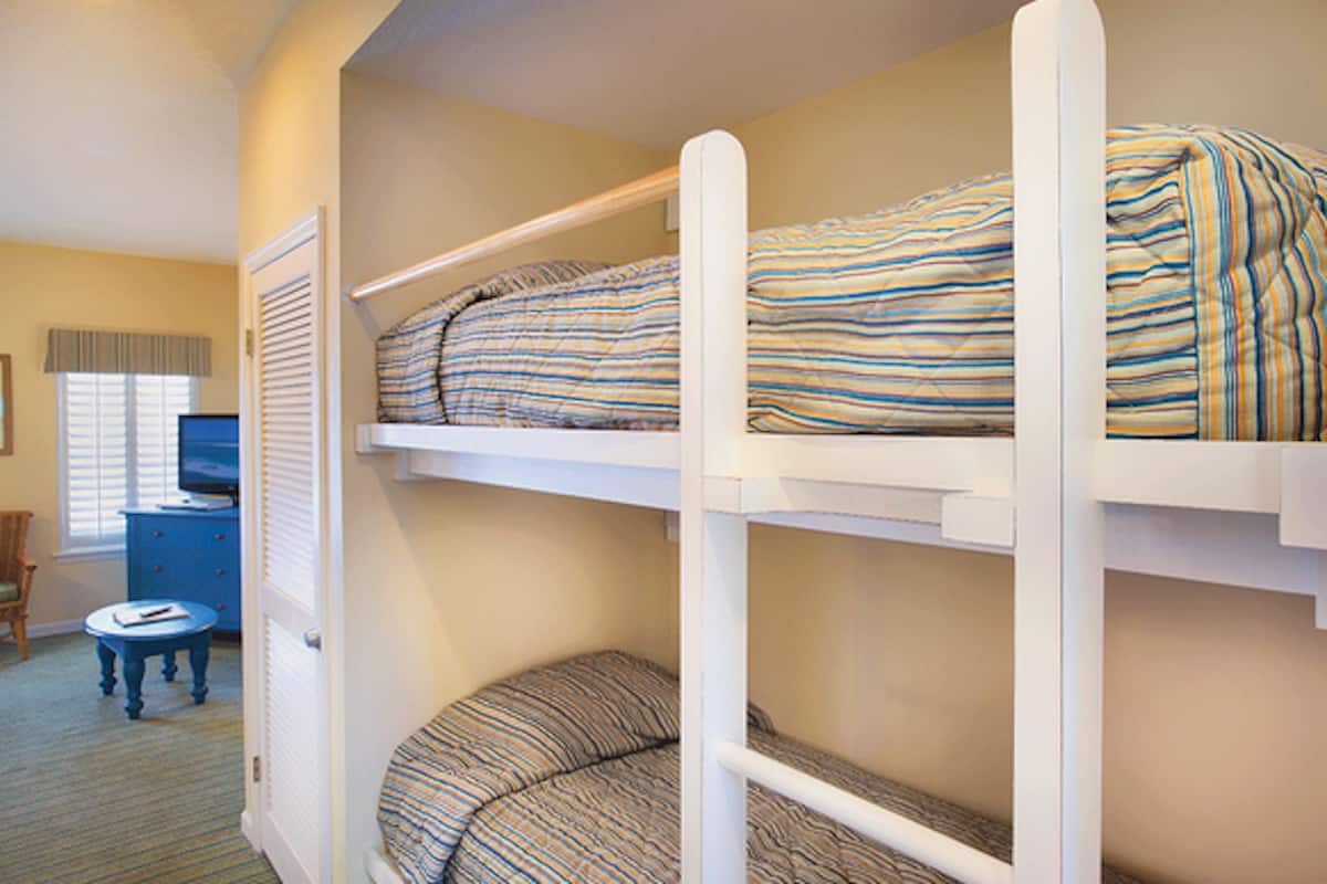 A room with bunk beds, a small round table, a chair, and a television.