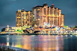 Un hotel grande de varios pisos con vista al agua, que cuenta con balcones y diversas opciones de restaurantes y recreación.