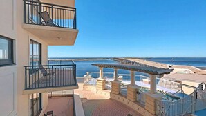Een balkon met uitzicht op zee, een zwembadgedeelte en buitenmeubilair.