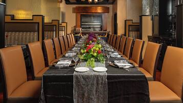 Una larga mesa de comedor dispuesta para una comida formal, con un centro decorativo, rodeada de sillas de cuero.