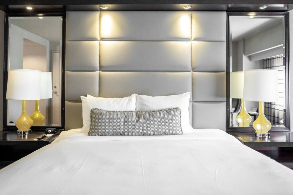 Een moderne hotelkamer met een groot bed, een gestoffeerd hoofdbord en twee bedlampen.