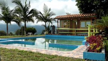 Relax by the serene pool surrounded by lush greenery and palm trees.
