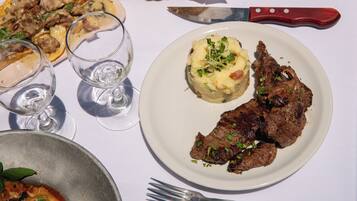 A plate with meat and mashed potatoes, two glasses of water, and a knife on a table.
