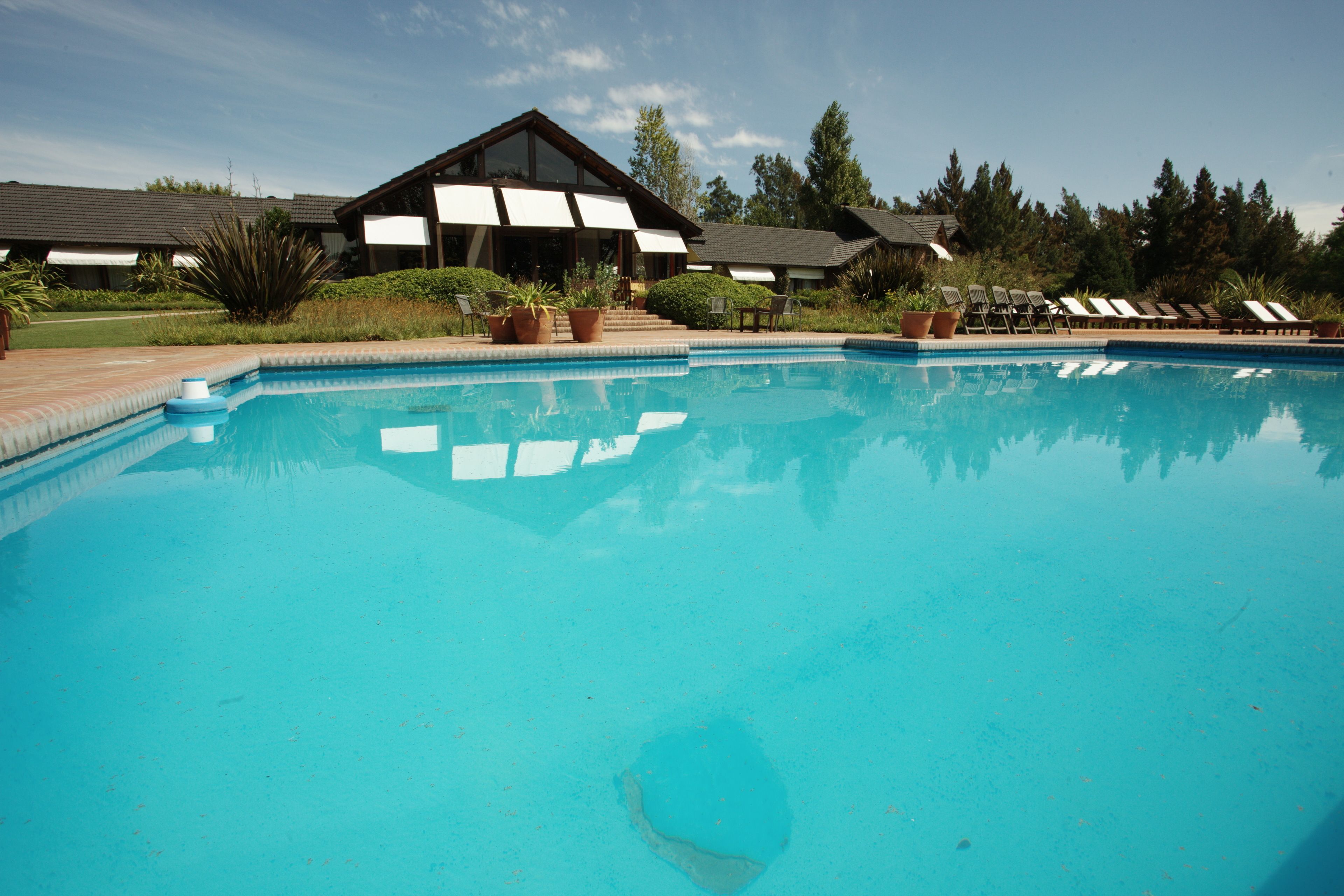 A swimming pool with lounge chairs and a building with large windows in the background.