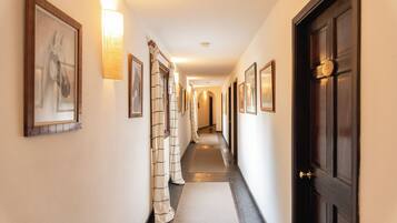 Passadís d'hotel amb quadres emmarcats, una porta de fusta i un paviment amb moqueta.
