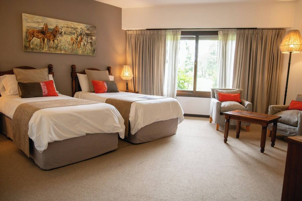 Ein Hotelzimmer mit zwei Betten, einem Sofa, einem Tisch und einem Bild an der Wand.