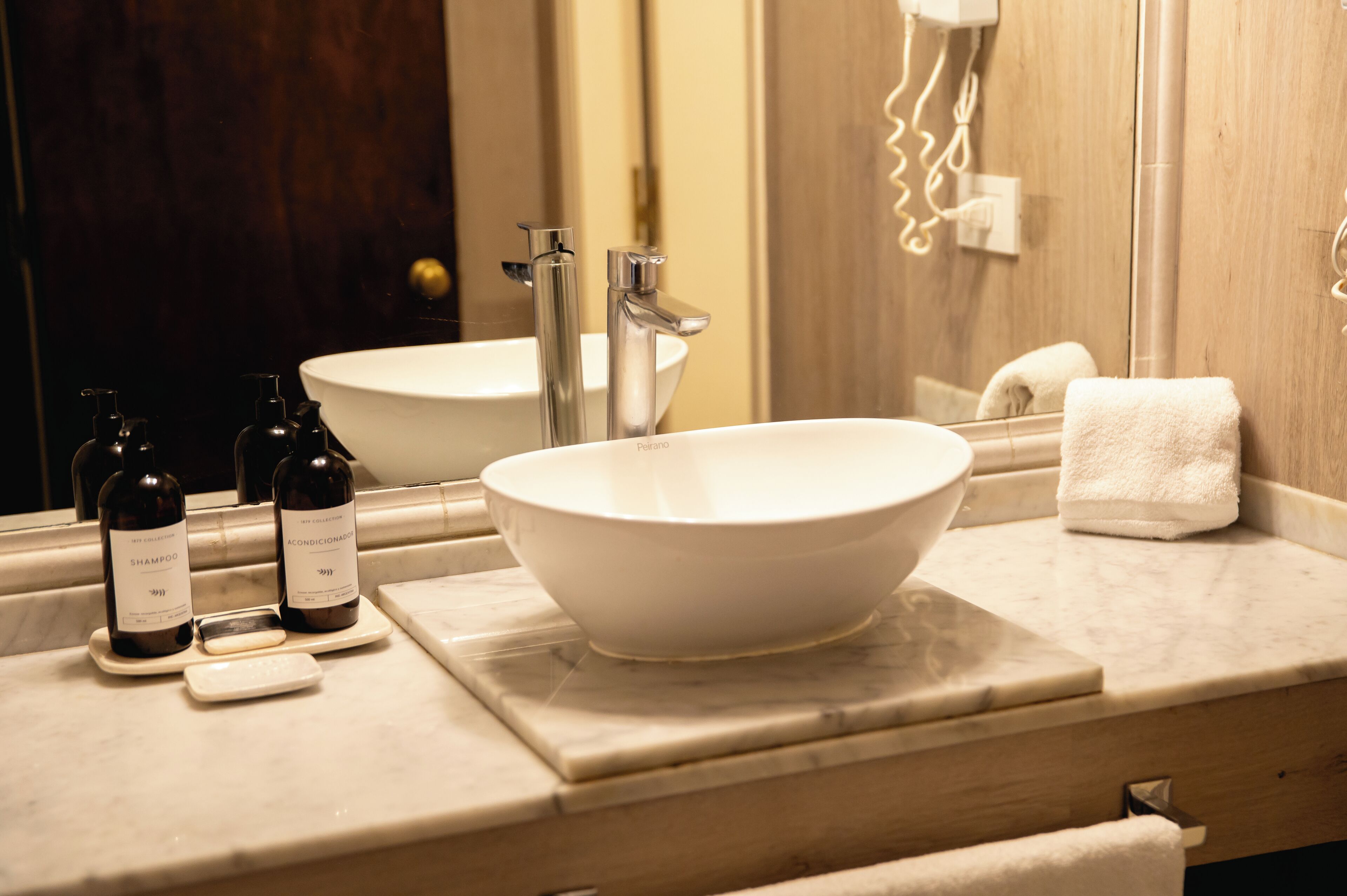 A bathroom with a large white sink, a mirror, and two bottles of shampoo and conditioner.