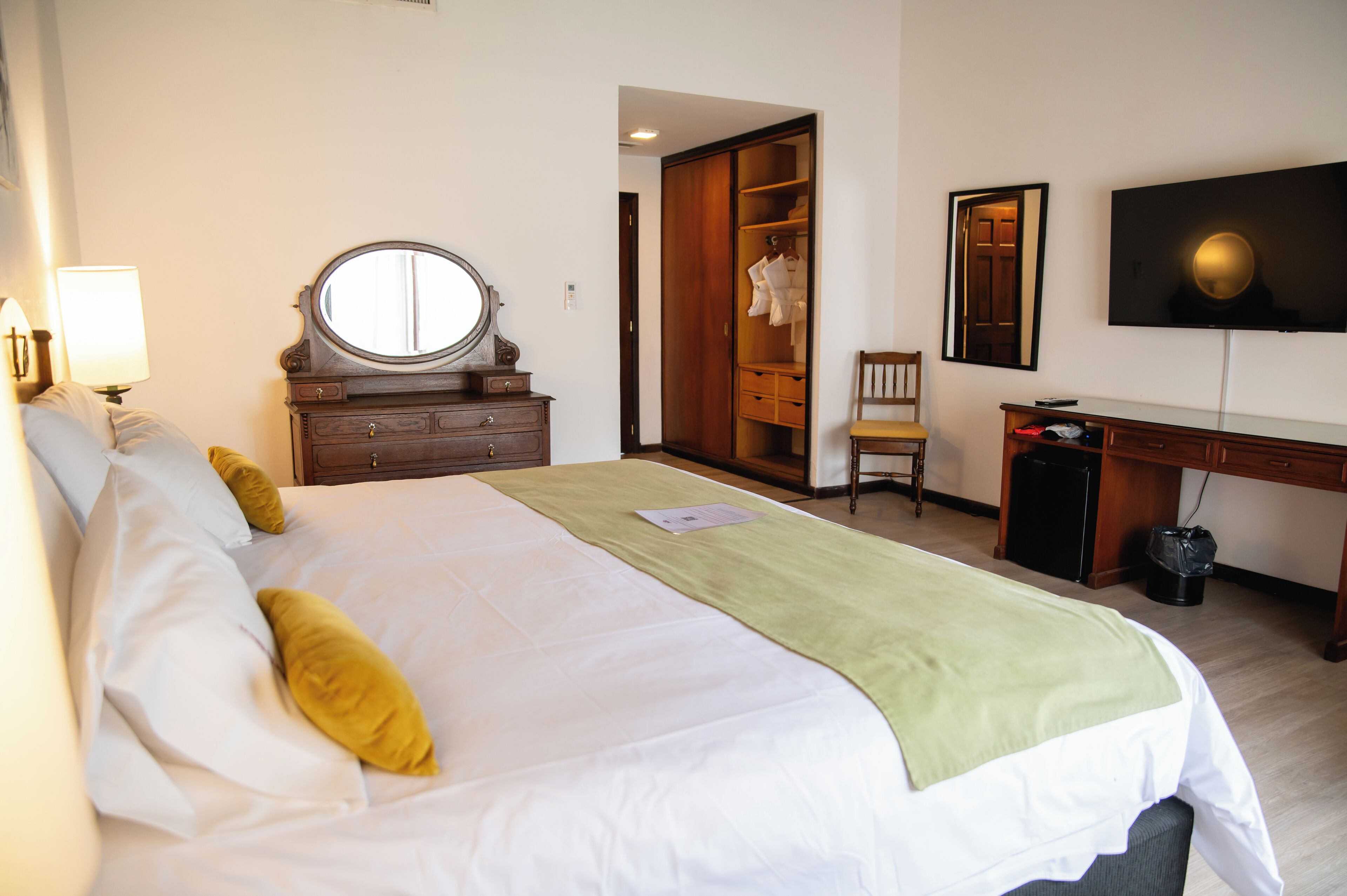 A hotel room with a bed, a desk, a chair, a wardrobe, and a TV.