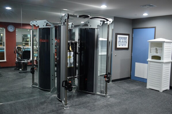 A gym with weight machines, a clock, and a framed picture on the wall. - Del-Mar Airport Inn & Suites (Shreveport)