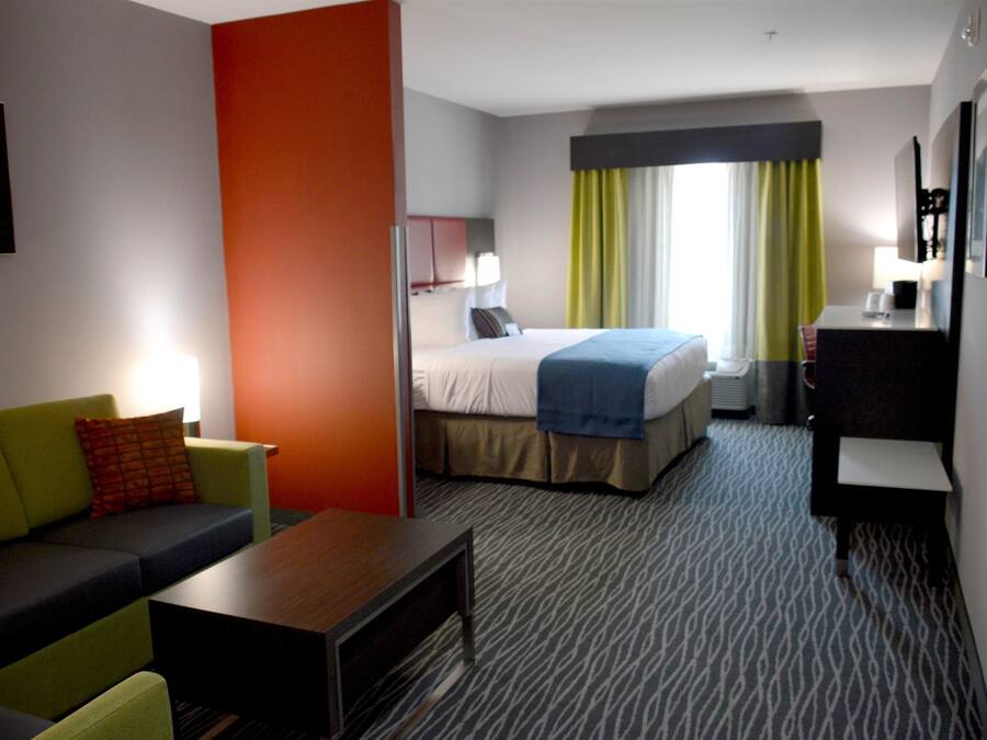 Quarto de hotel com cama, sofá, escrivaninha e cómoda.