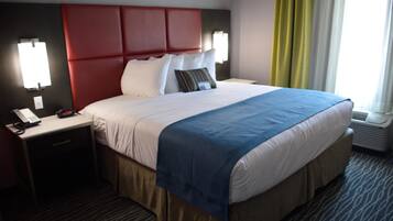 A hotel room with a large bed, a nightstand with a phone, and a window with curtains.