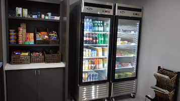 Two beverage dispensers stocked with various drinks and snacks, a shelf with packaged goods, and a wicker basket.