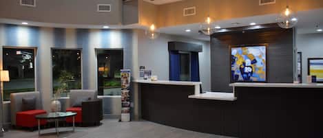 A modern reception area with a curved desk, seating, and a large abstract painting.