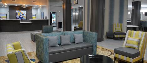 A modern lobby with a reception desk, seating area, and a large window.