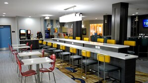 Un moderno vestíbulo de hotel con zona de bar, asientos y una pantalla de televisión.