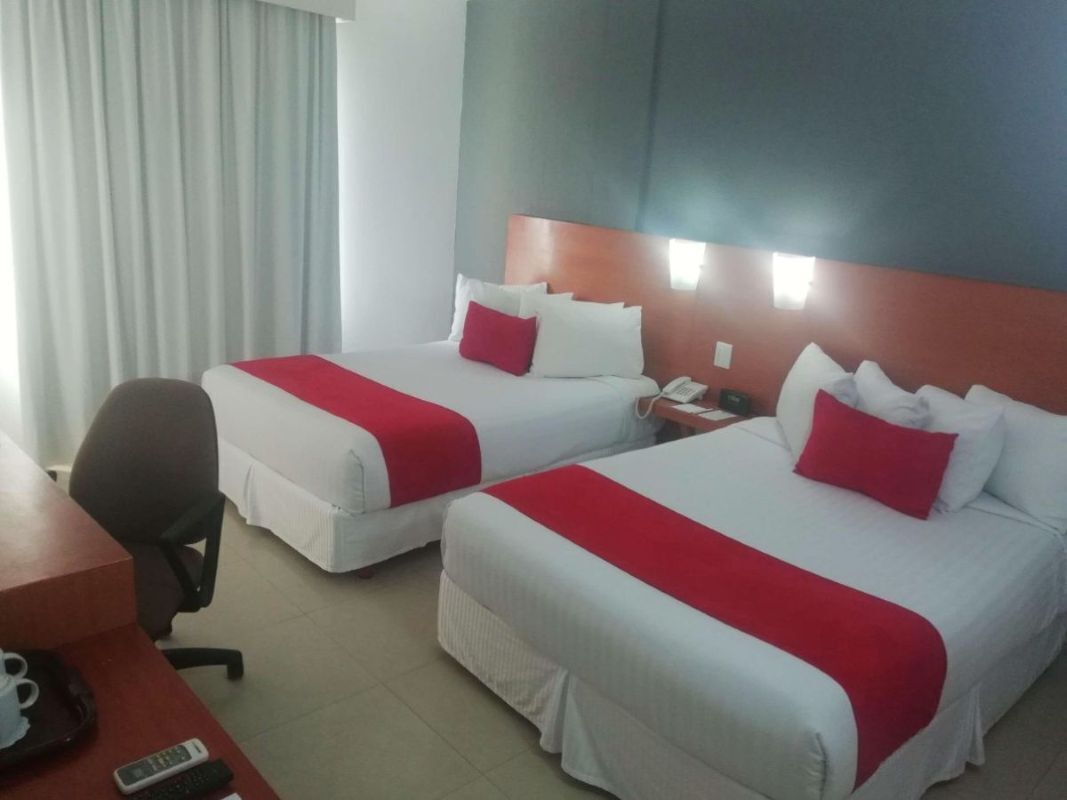 Habitación de hotel con dos camas, un escritorio, una silla y un teléfono.
