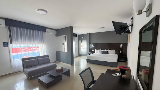 A modern hotel room with a large bed, a sofa, a desk, and a dining table. - Days Inn by Wyndham Minatitlan (Minatitlán)