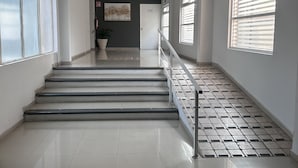 A spacious, modern interior with a staircase leading to a door, large windows with blinds, and a tiled floor. - Days Inn by Wyndham Minatitlan (Minatitlán)