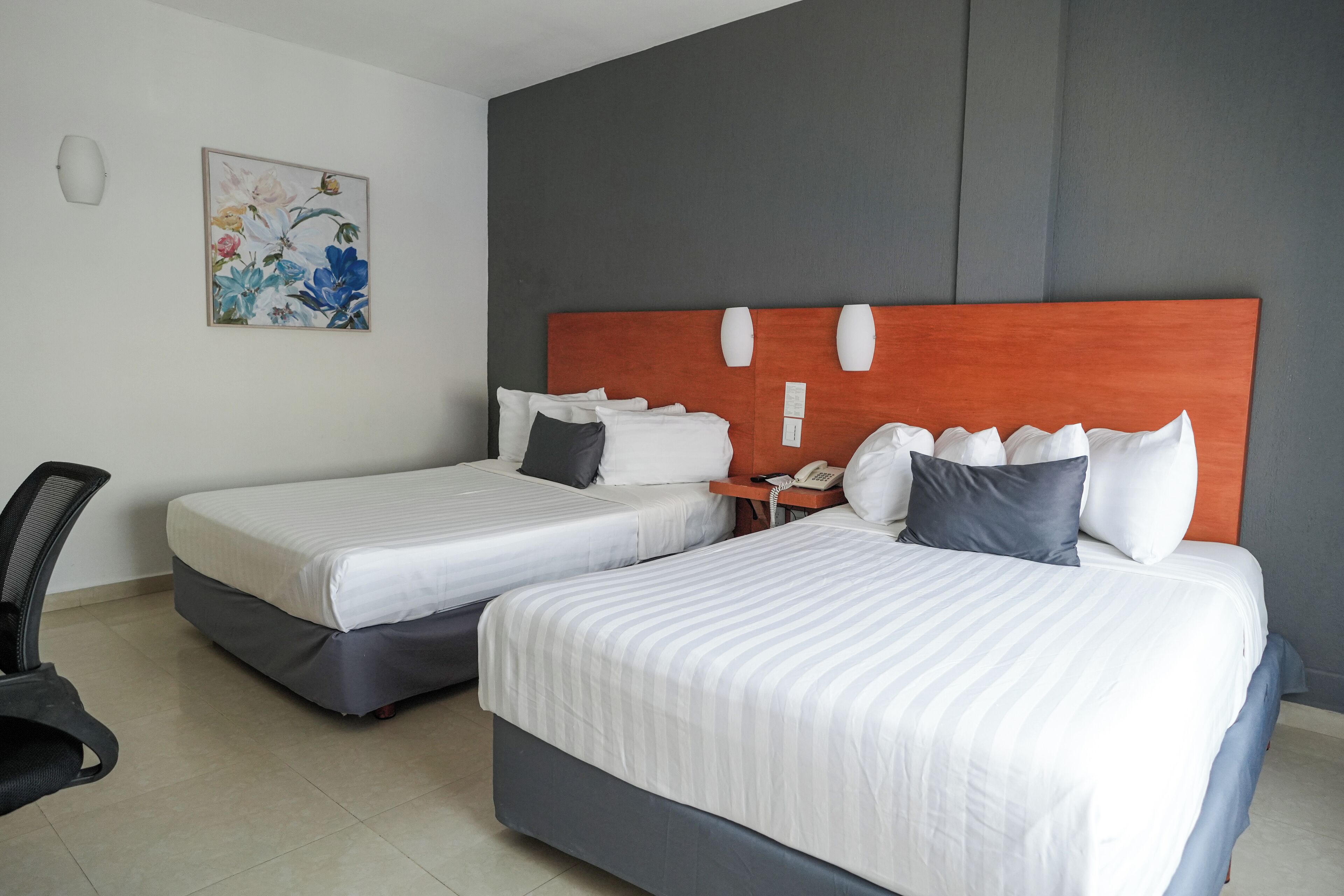 Een hotelkamer met twee bedden, een bureau en een stoel.